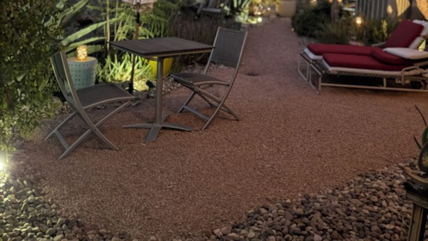 An outdoor patio with a table and chairs, a lounge chair, and a decorative umbrella.