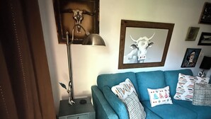 A living room with a teal sofa, a red throw blanket, a lamp, and artwork on the wall.