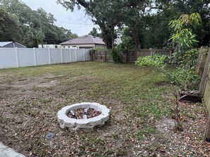 A backyard with a circular stone fire pit surrounded by grass and scattered leaves. - Perfect 3-bedroom house with AC in awesome St. Petersburg (St. Petersburg)