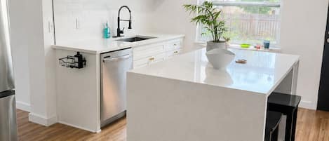 A modern kitchen with white cabinetry, a central island, and a window providing a view of the outdoors.