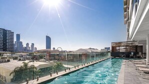 Piscina en la azotea con vista al horizonte de la ciudad, rodeada de edificios modernos.