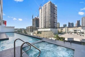 Ein Pool auf dem Dach mit Blick auf Hochhäuser und Baukräne.