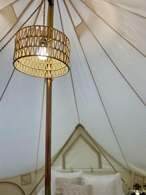 A tent with a bed, a hanging light fixture, and a window.