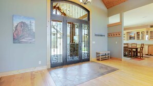 Un interior espaiós amb una gran porta de fusta, una zona de menjador amb cadires i una cuina visible a través d'una volada.