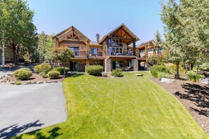 A large, two-story log cabin with a stone foundation, multiple windows, and a well-maintained lawn. - Above The Crest - Views! Elegantly Perched, Hot Tub, Table Tennis, Luxury, Peaceful (Redmond)