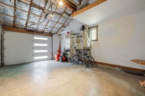 Eine Garage mit Betonboden, einem Fahrrad, einer roten Rasenmäher und einem weißen Regal an der Wand.