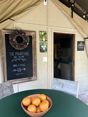 Un intérieur rustique avec un tableau noir servant de panneau, une porte en bois et une table ornée d’oranges.