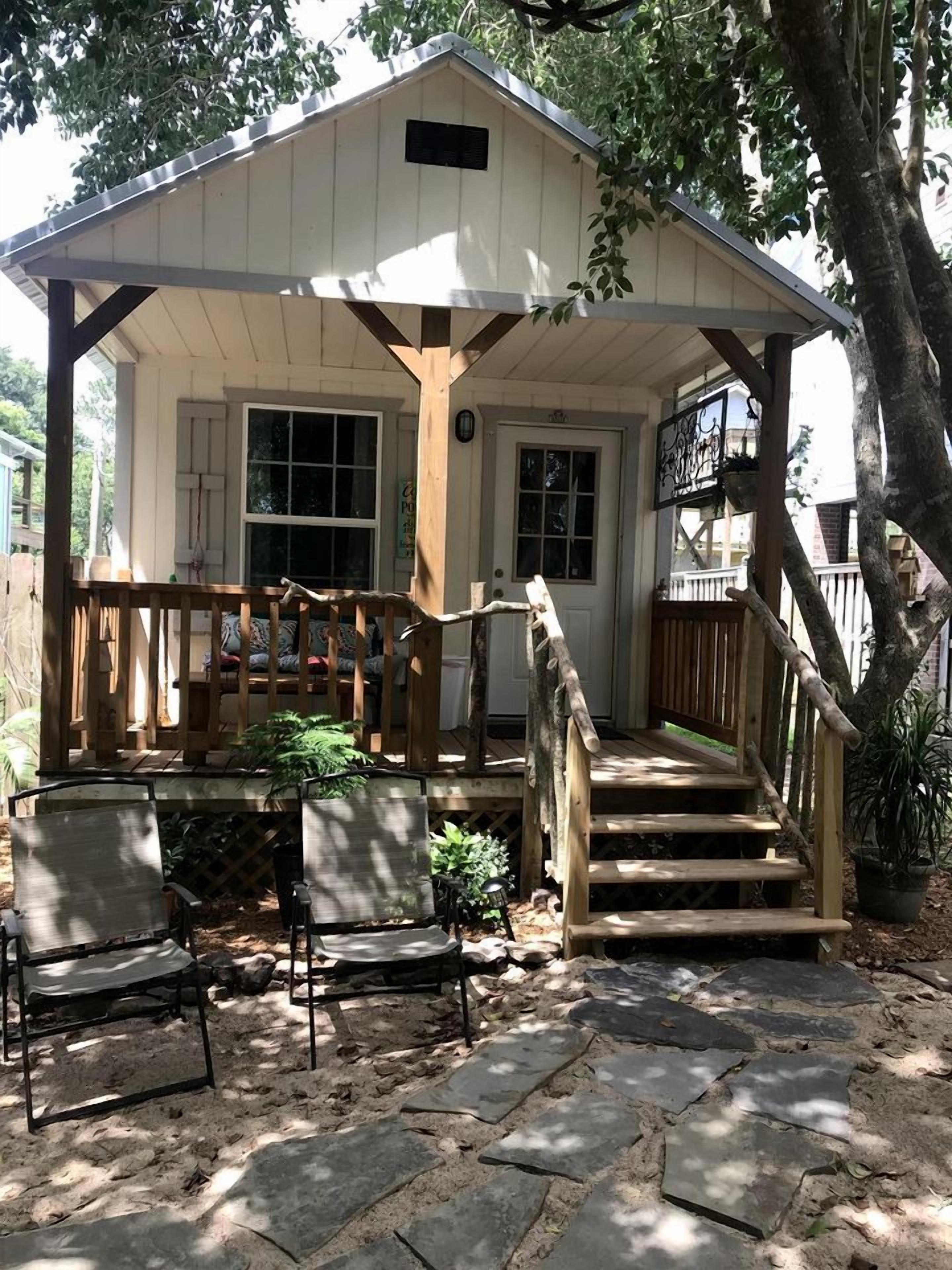 Eine Holzhütte mit Veranda, Treppe und Gartenmöbeln.