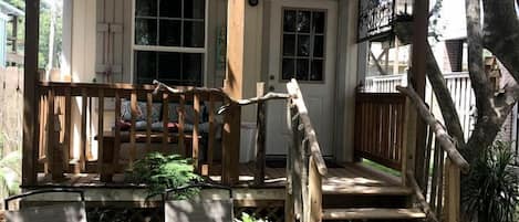 Eine Holzhütte mit Veranda, Treppe und Gartenmöbeln.