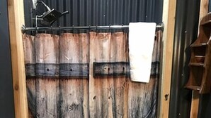 Eine Holztür mit rustikalem Design, ein Handtuch hängt an der Tür und ein Korb mit Gegenständen steht auf dem Boden.