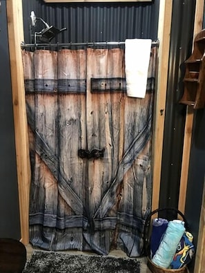 Eine Holztür mit rustikalem Design, ein Handtuch hängt an der Tür und ein Korb mit Gegenständen steht auf dem Boden.