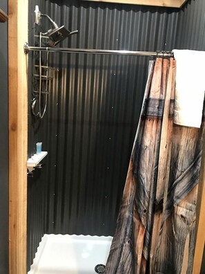 A shower area with a metal showerhead, a white sink, and a wooden shower curtain. - Peaceful Cottage Escape with Private Porch & Nature Views in Bacliff, Texas (Bacliff)