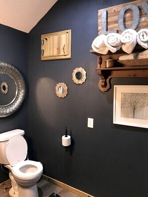 A bathroom with a toilet, wall-mounted towel rack, and decorative wall art.