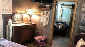 Ein Schlafzimmer mit Bett, Kommode, Spiegel und Fernseher.