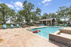 A swimming pool with lounge chairs and a covered pavilion.