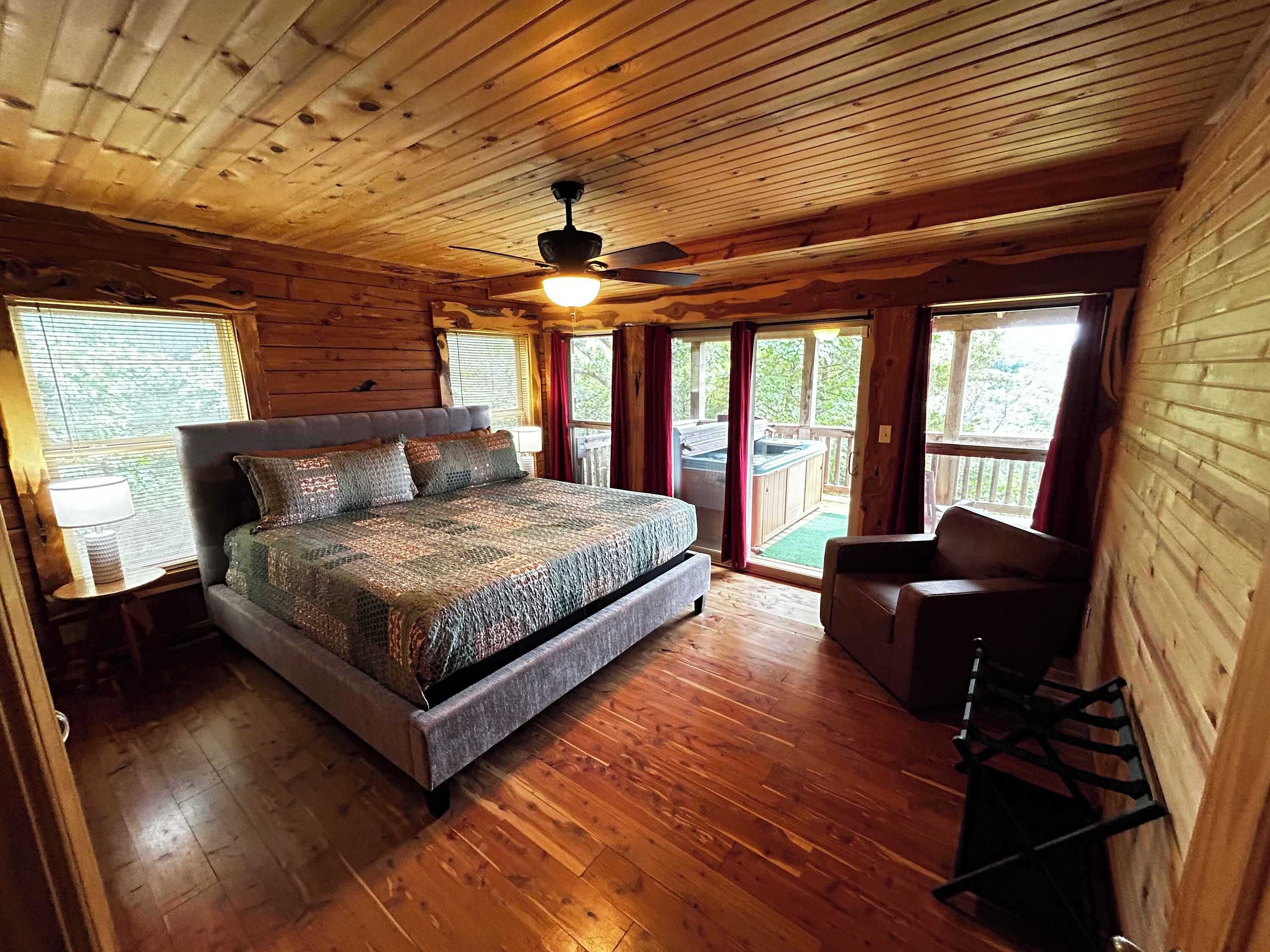 Dormitorio de cabaña de madera con cama, mesita de noche, silla y balcón.