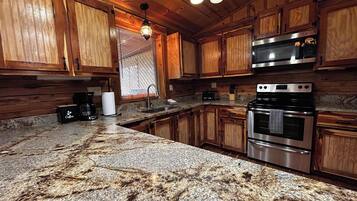 Una cocina con armarios de madera, encimeras de granito, horno de acero inoxidable y cafetera.