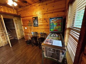 A wooden interior with a pinball machine, a framed game, and a staircase. - Hot Tub, Pool Table, Sunset Views (Eureka Springs)