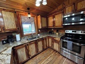 A kitchen with wooden cabinets, a stainless steel stove, a toaster, and a coffee maker. - Hot Tub, Pool Table, Sunset Views (Eureka Springs)