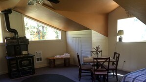 A room with a fireplace, a dining table with chairs, a window, and two beds. - Charming Loft-Style Cabin Rental for Six near Missoula, Montana (Hall)