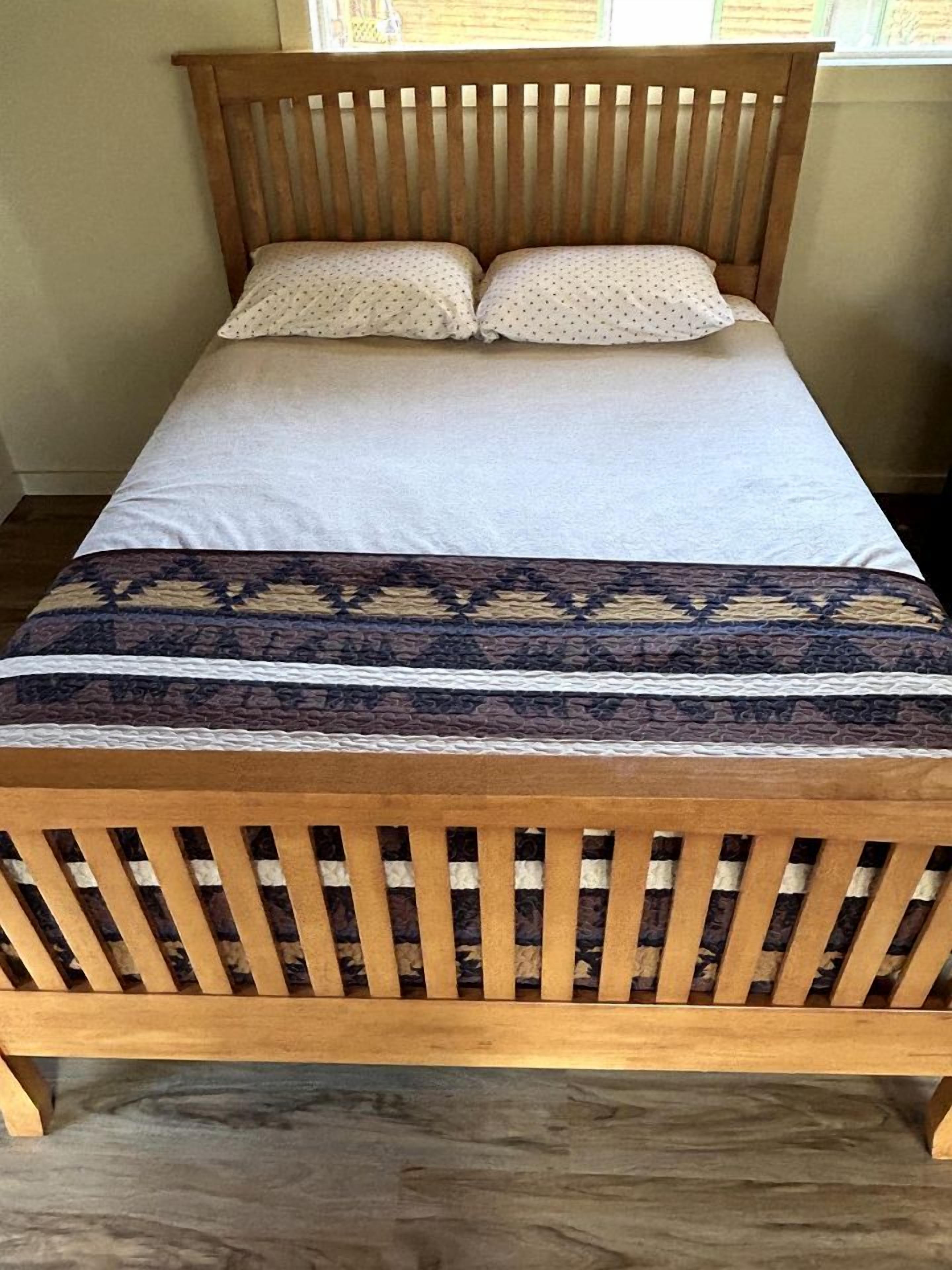 Un lit en bois avec une couvre-lit à motifs et deux oreillers.
