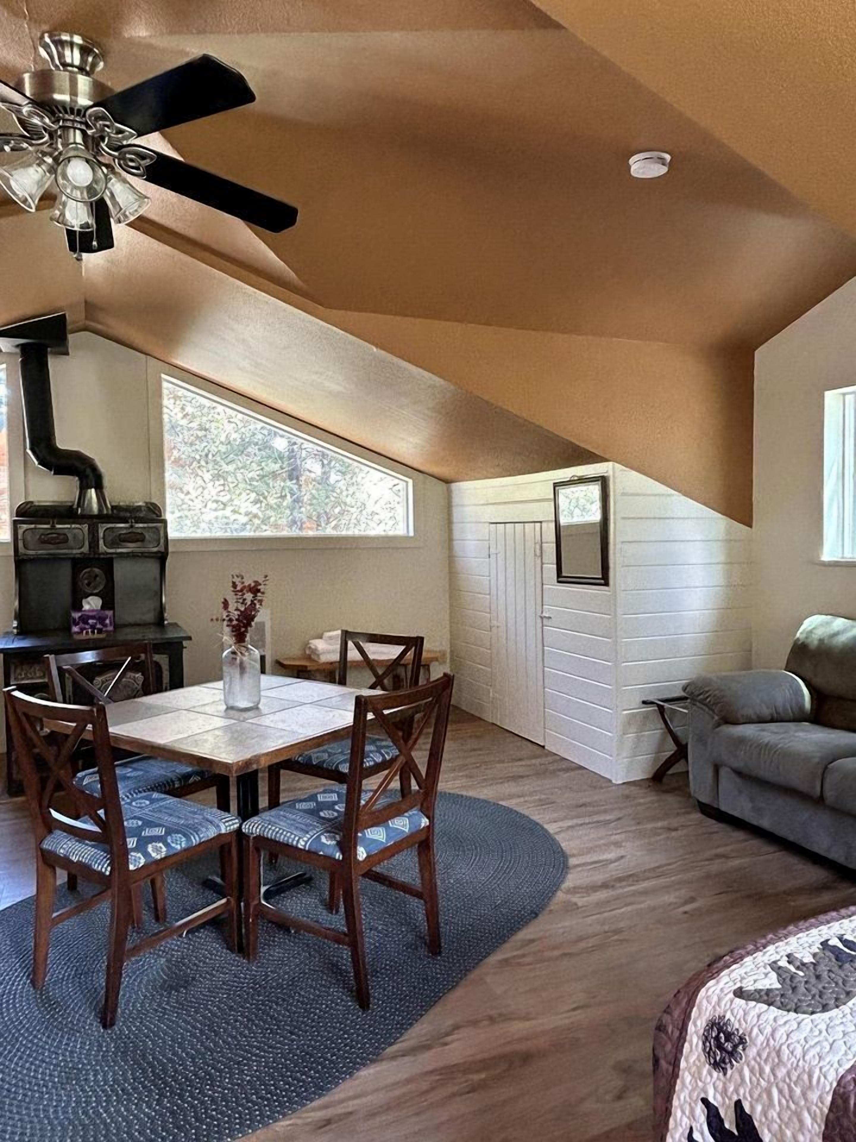 A dining area with a table and chairs, a ceiling fan, a fireplace, and a window providing natural light.