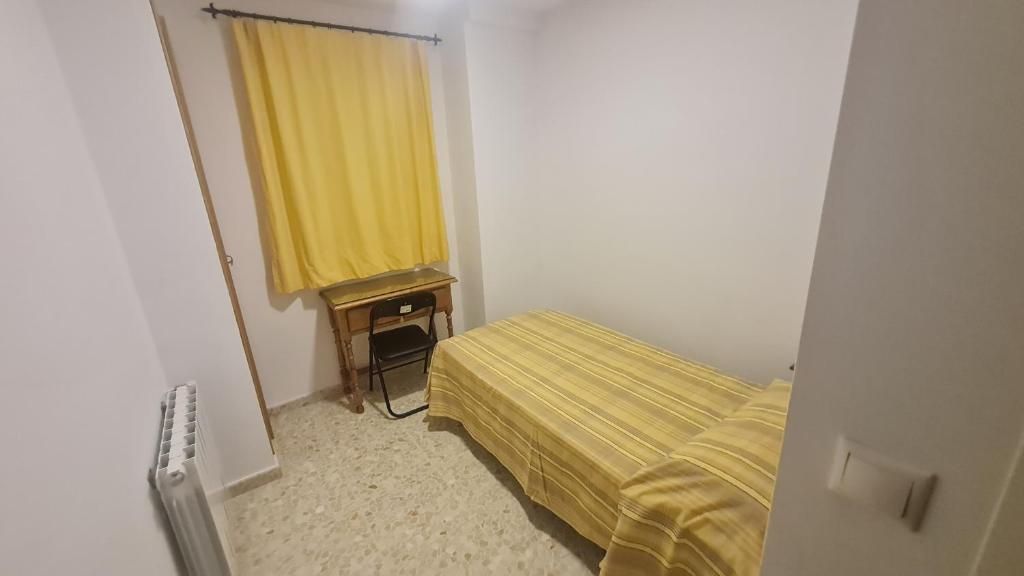 A small room with a bed, a desk, and a chair.