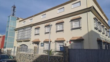 Un edificio con múltiples ventanas, una pared de piedra y una cerca de metal.