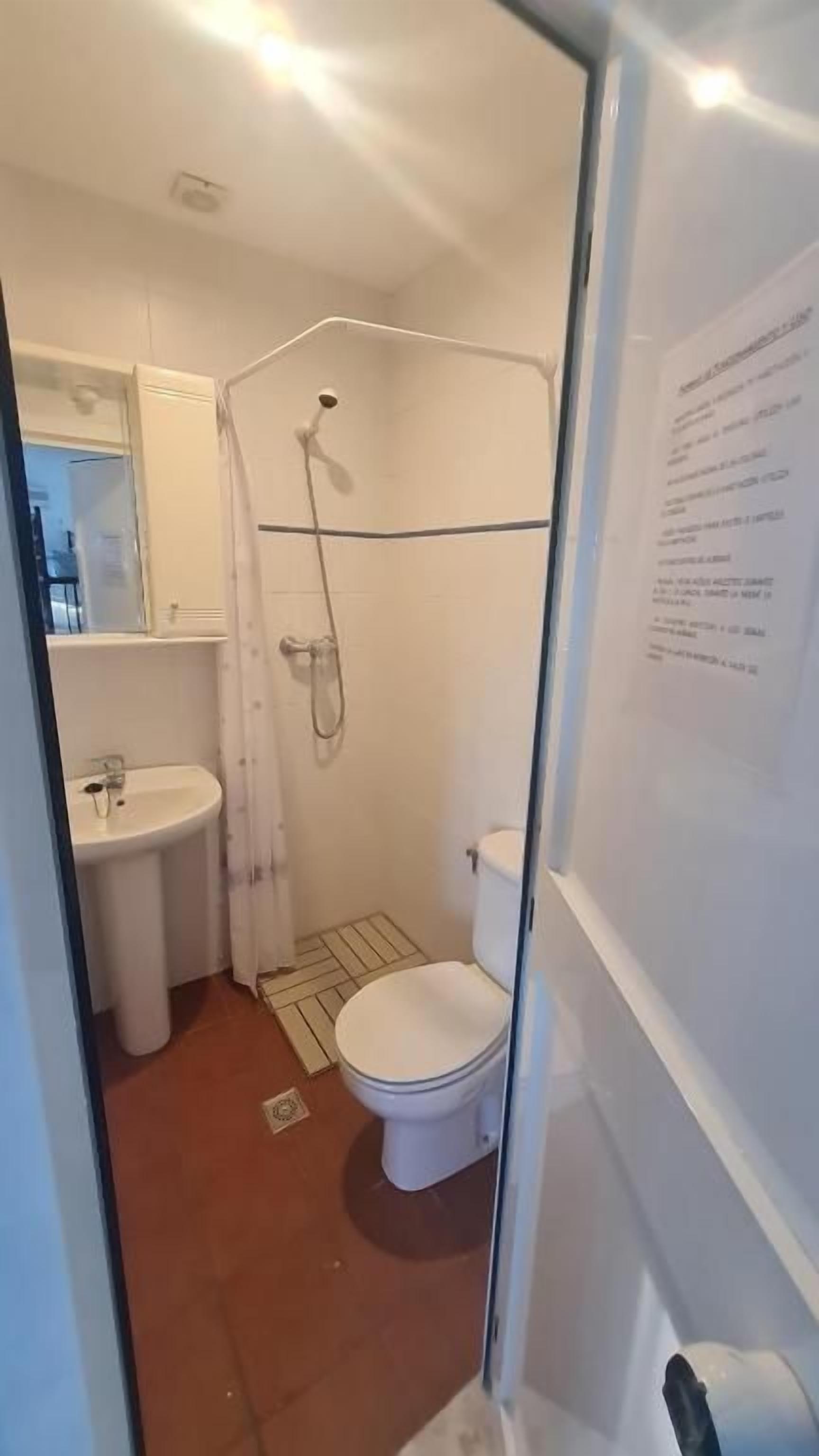 Un baño pequeño con ducha, inodoro y lavabo.