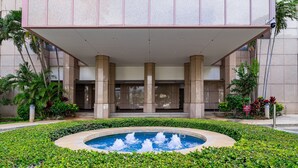 A hotel entrance with a pool and a covered area with columns. - 27th-floor Waikiki Suite with Panoramic Mountain/Canal/City Views (Honolulu)