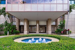 Ein Hotel Eingang mit Pool und überdachtem Bereich mit Säulen.