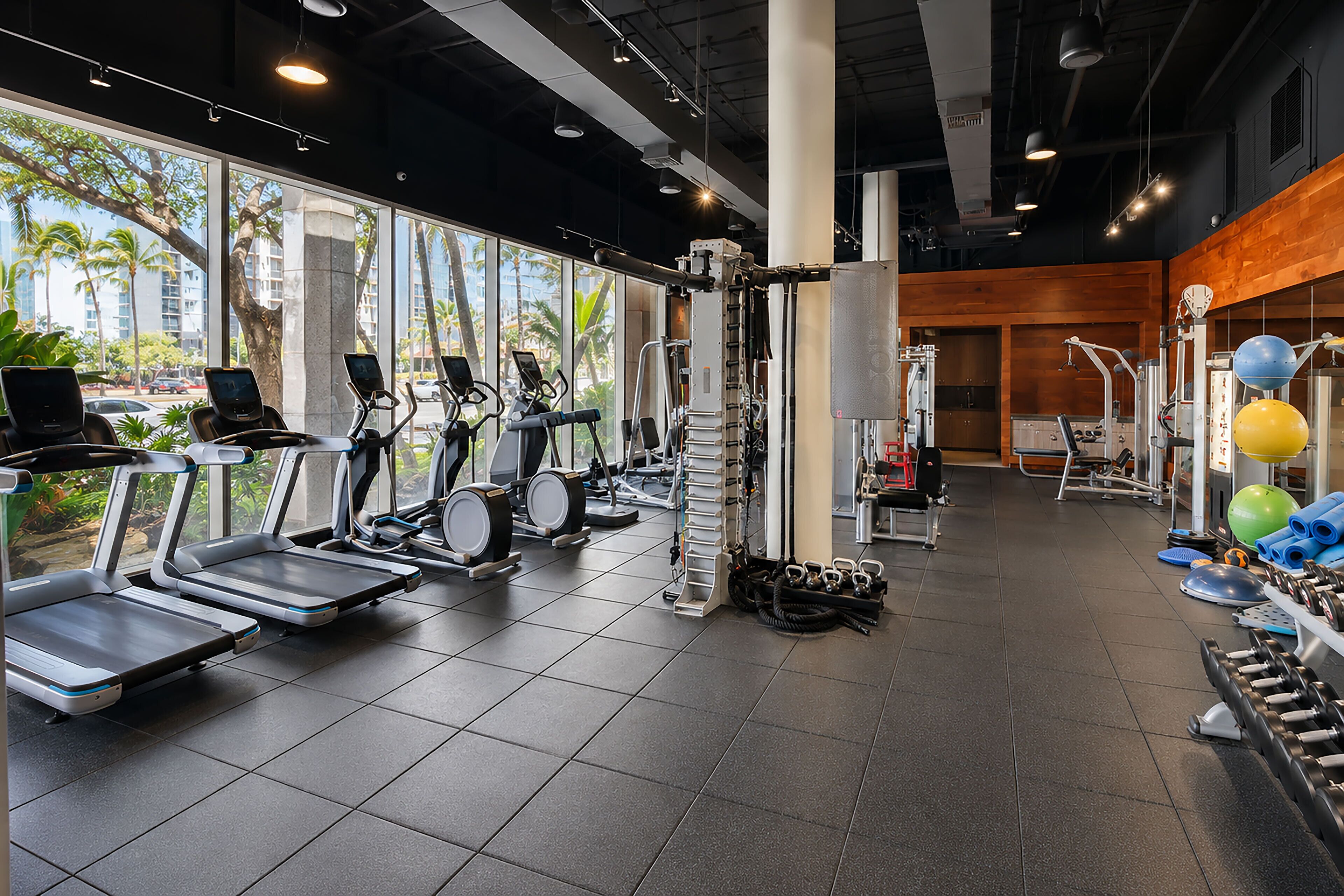 Un gimnasio con cintas de correr, elípticas y pesas libres.