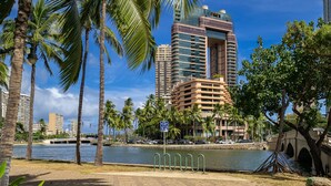 A waterfront hotel with palm trees, a bridge, and a body of water. - 27th-floor Waikiki Suite with Panoramic Mountain/Canal/City Views (Honolulu)