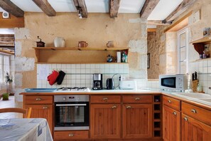 A kitchen with wooden cabinets, a stove, a microwave, and a coffee maker.