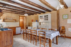 A rustic kitchen with wooden beams, a tiled backsplash, and a dining area with wooden chairs and a table. - Set of Holiday Homes - Swallows and Poultry (Lusignan)