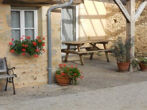 Un espace extérieur aménagé dans un style rustique, avec un banc en bois et des plantes en pot.