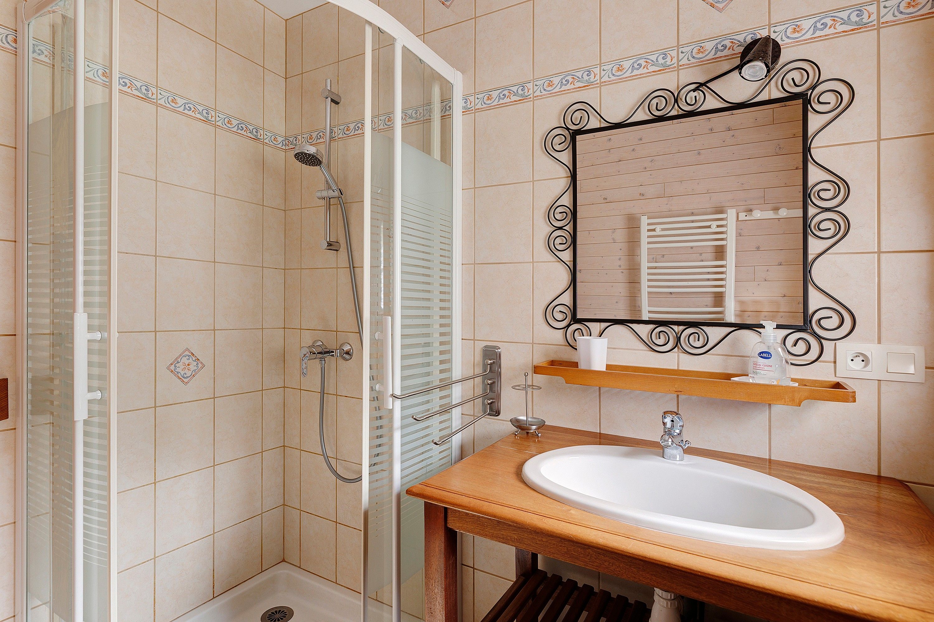 Un bagno con doccia, lavandino, specchio e porta asciugamani.