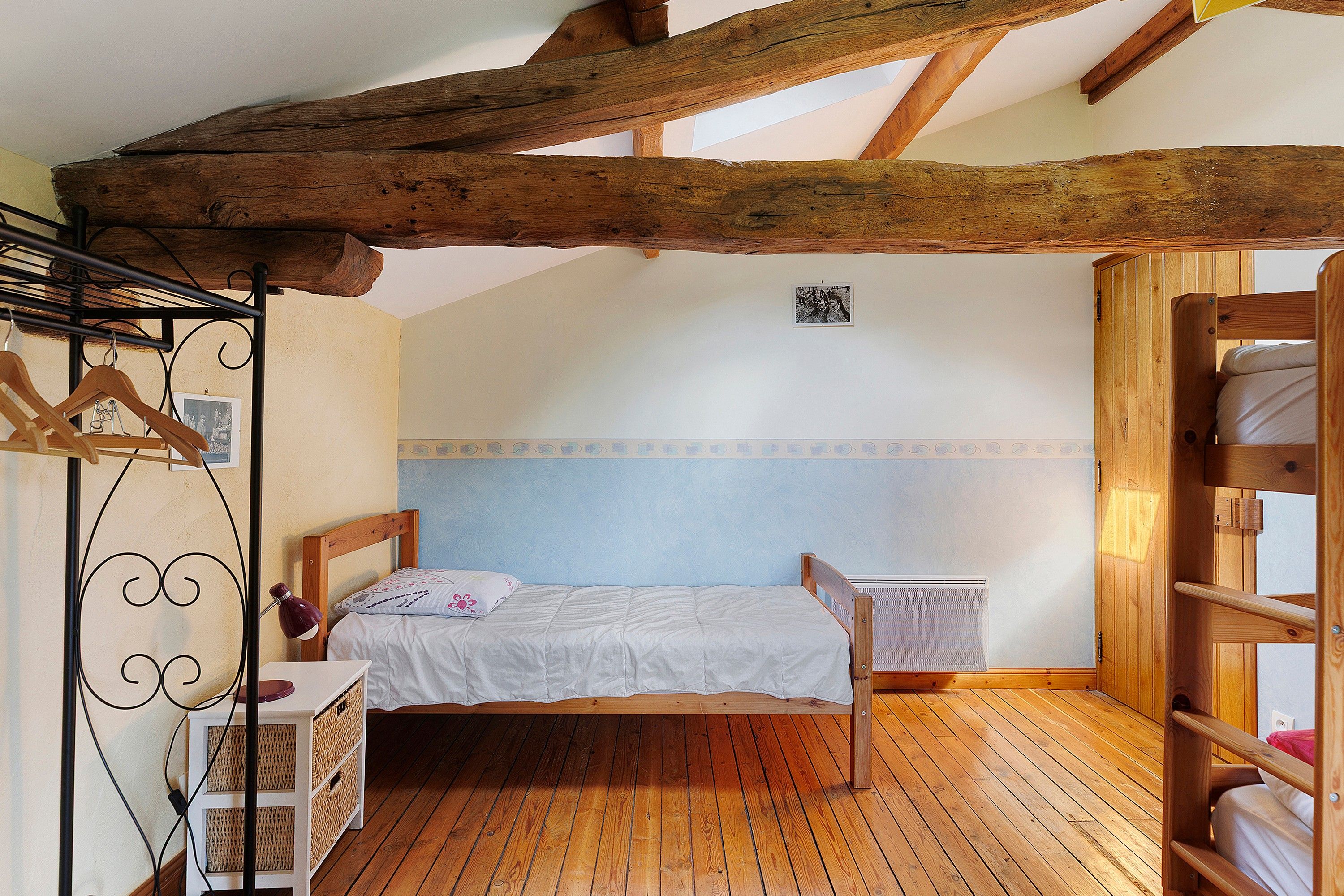 Een slaapkamer met een houten bed, een nachtkastje, een hanglamp en een kledingkast.