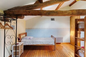 A bedroom with a wooden bed, a bedside table, a hanging lamp, and a wardrobe. - Set of Holiday Homes - Swallows and Poultry (Lusignan)