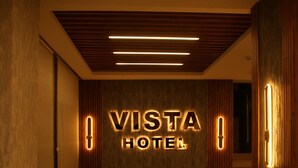 Un vestíbulo de hotel con un letrero que dice 'VISTA HOTEL', sillas de cuero, un sofá y un techo de madera.