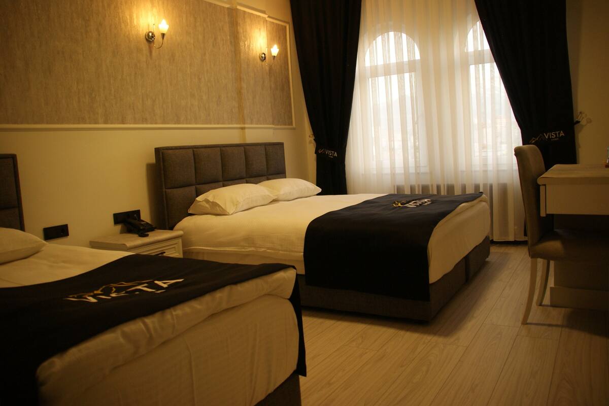 A hotel room with two beds, a desk, and a chair.