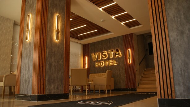 Un moderno vestíbulo de hotel con mostrador de recepción, zona de estar y una escalera que conduce a otras plantas.
