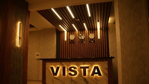 Un mostrador de recepción con letras iluminadas que dicen 'VISTA', un reloj y un cartel que dice 'Nueva York'.