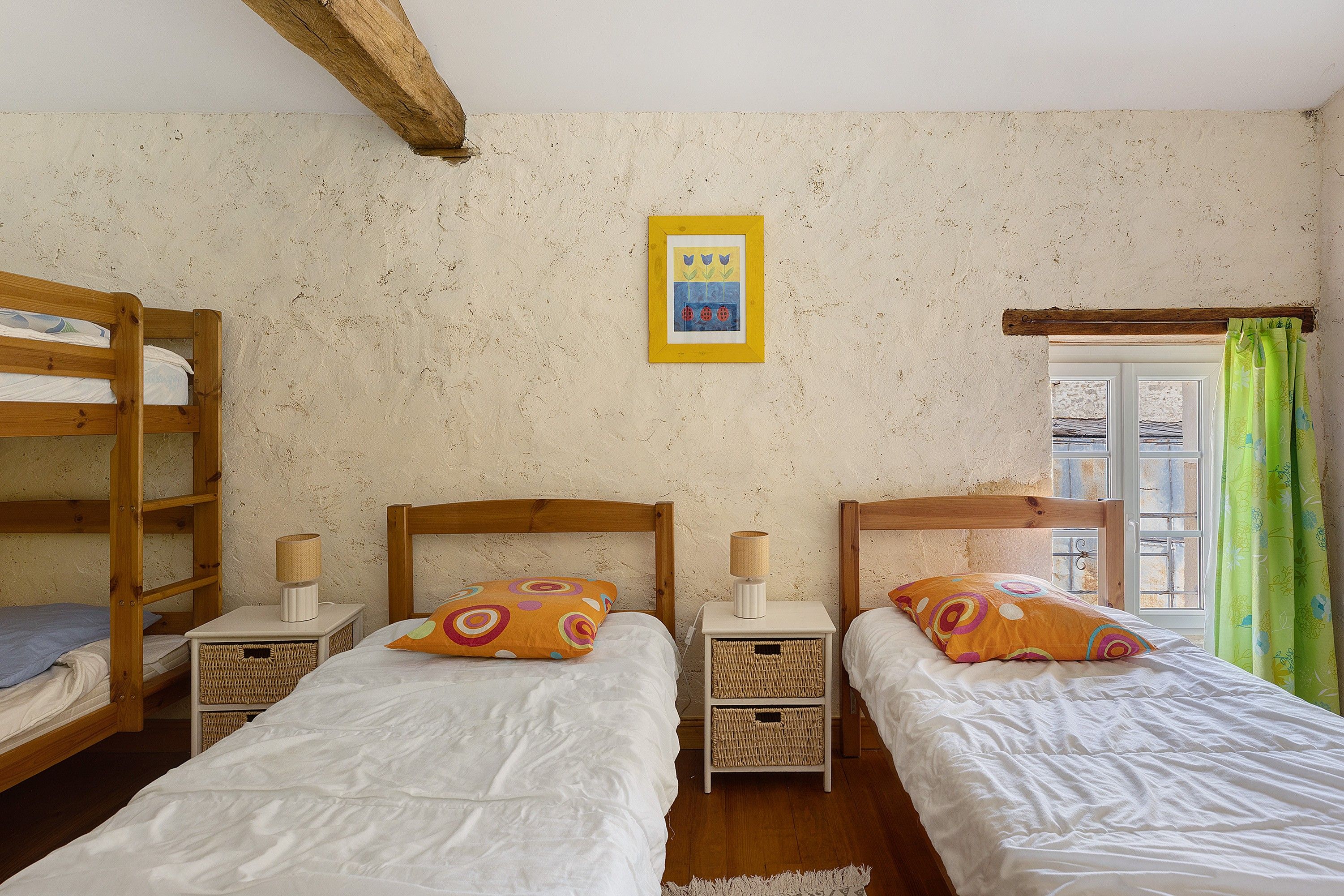 Une chambre avec deux lits superposés en bois, chacun doté d’une table de chevet et d’une lampe, et un tableau encadré accroché au mur.
