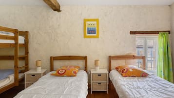 Une chambre avec deux lits superposés en bois, chacun doté d’une table de chevet et d’une lampe, et un tableau encadré accroché au mur.