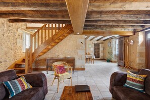 Un intérieur rustique avec des poutres apparentes, une cheminée en pierre et un coin repas.