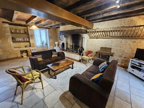 Una sala acogedora con chimenea, vigas de madera y un sofá.