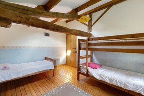 A room with two bunk beds, wooden beams on the ceiling, a small table, and a door. - Le Refuge des Oiseaux: Shared Terrace, Private Garden & Wi-Fi in Lusignan (Lusignan)