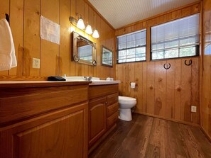 Un baño con paneles de madera, un lavamanos, un espejo y un inodoro.