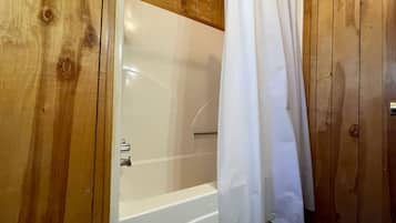 Un baño con paneles de madera, una bañera y una cortina de ducha.